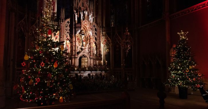 two Christmas trees twinkling in the low light of St Cuthbert Chapel at Ushaw Historic House, Chapels and Gardens.